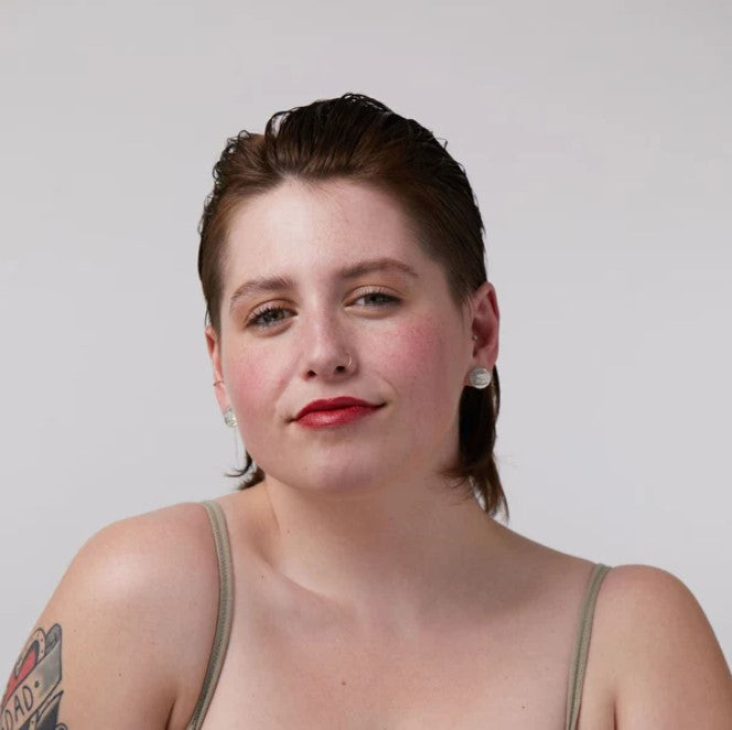 Close-up of Ruby Rebel Lip and Cheek Tint tube showing bold red color and textured matte finish on packaging lid surface.