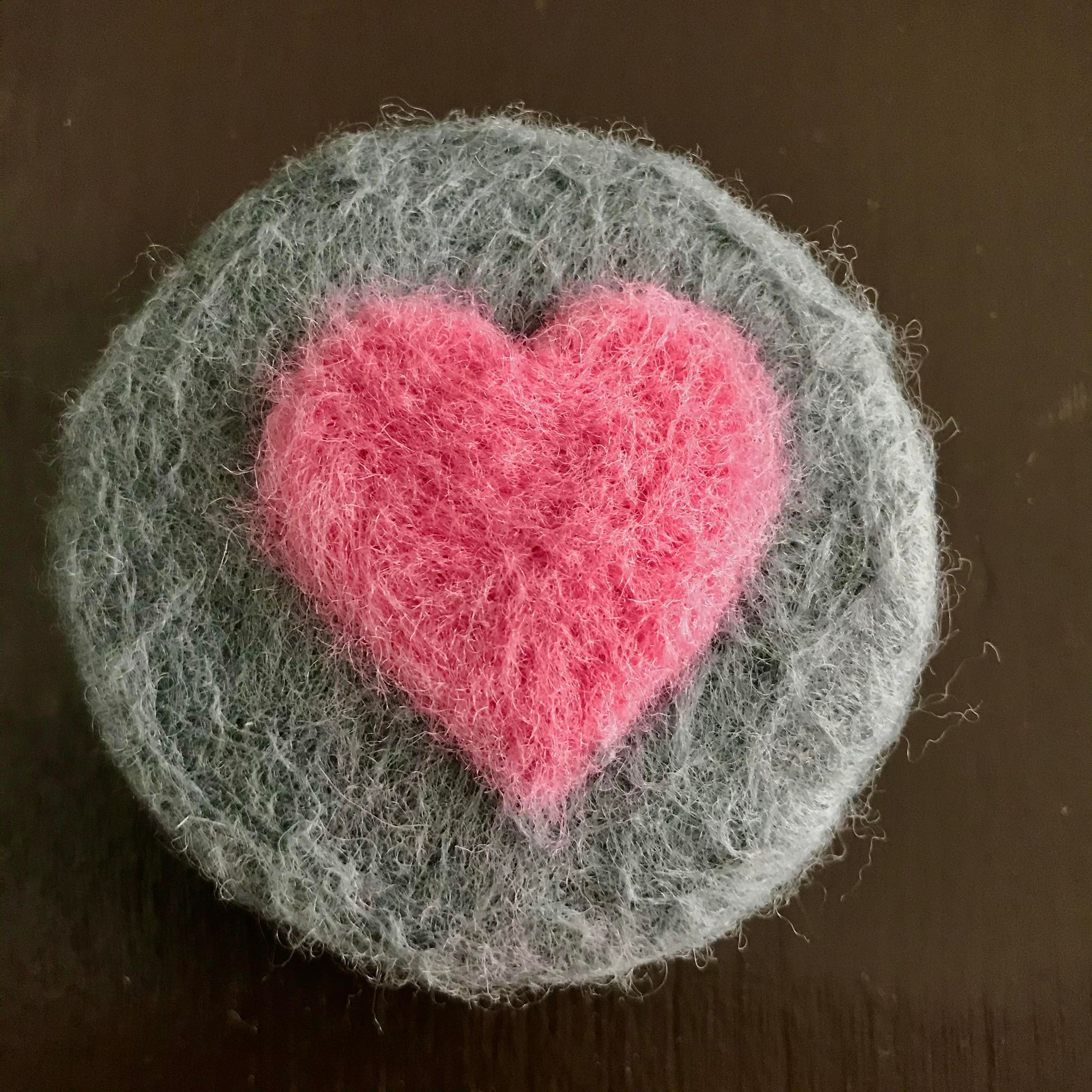 Close-up of felted soap’s textured surface revealing intricate fibers and subtle heart-shaped details on the side.