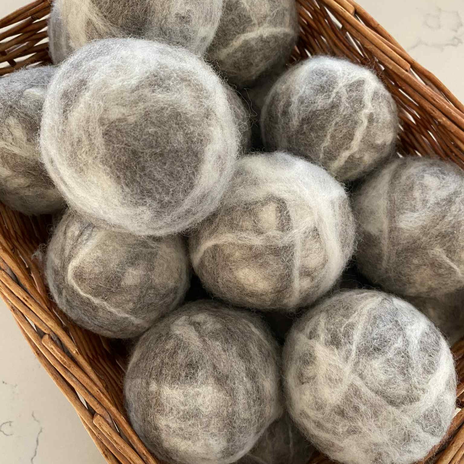 Close-up of three XL wool dryer balls showing textured felted surface and natural off-white color from a top-down angle.
