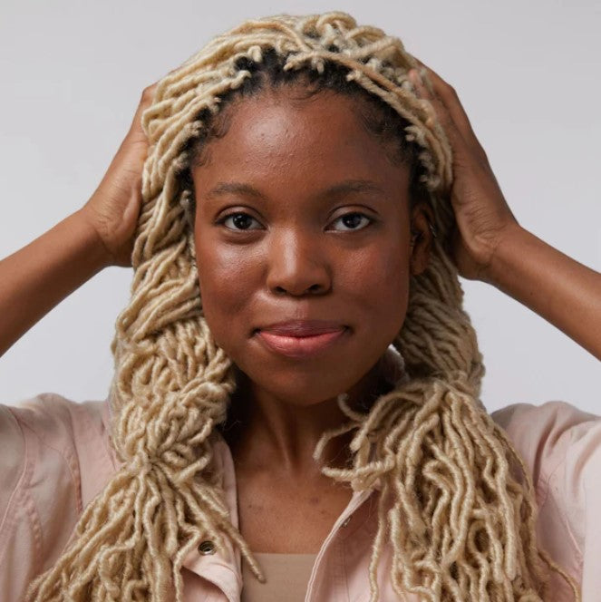 Close-up of the Sunset Seeker Lip and Cheek Tint tube showing vibrant coral color and matte finish on textured packaging