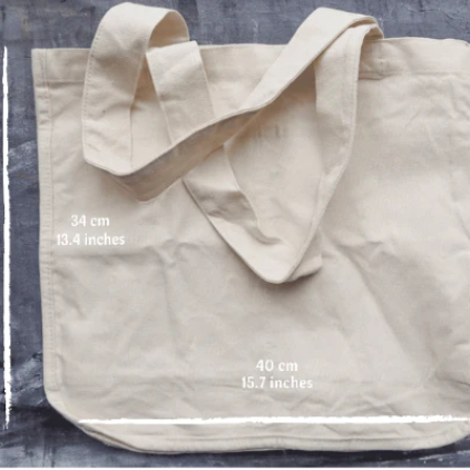 Close-up of black canvas tote bag handle with reinforced stitching and metal rivets for durability