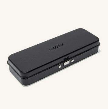 Close-up of The Leaf Travel Case’s textured matte metal surface with subtle engraved branding and sleek zipper detail from a