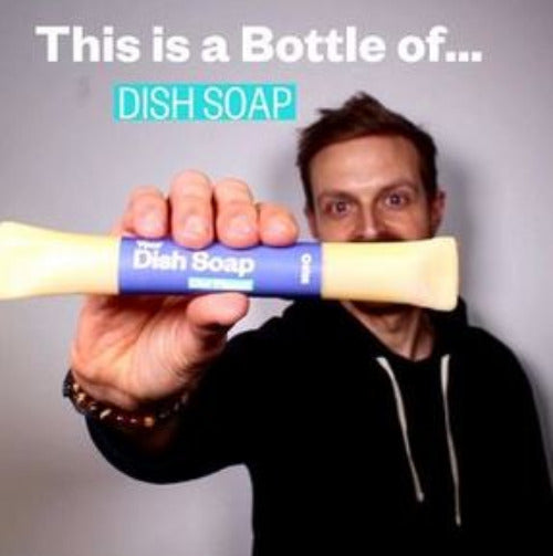 Close-up of clear, amber-colored dish soap concentrate in a cylindrical bottle with a blue screw cap and textured label