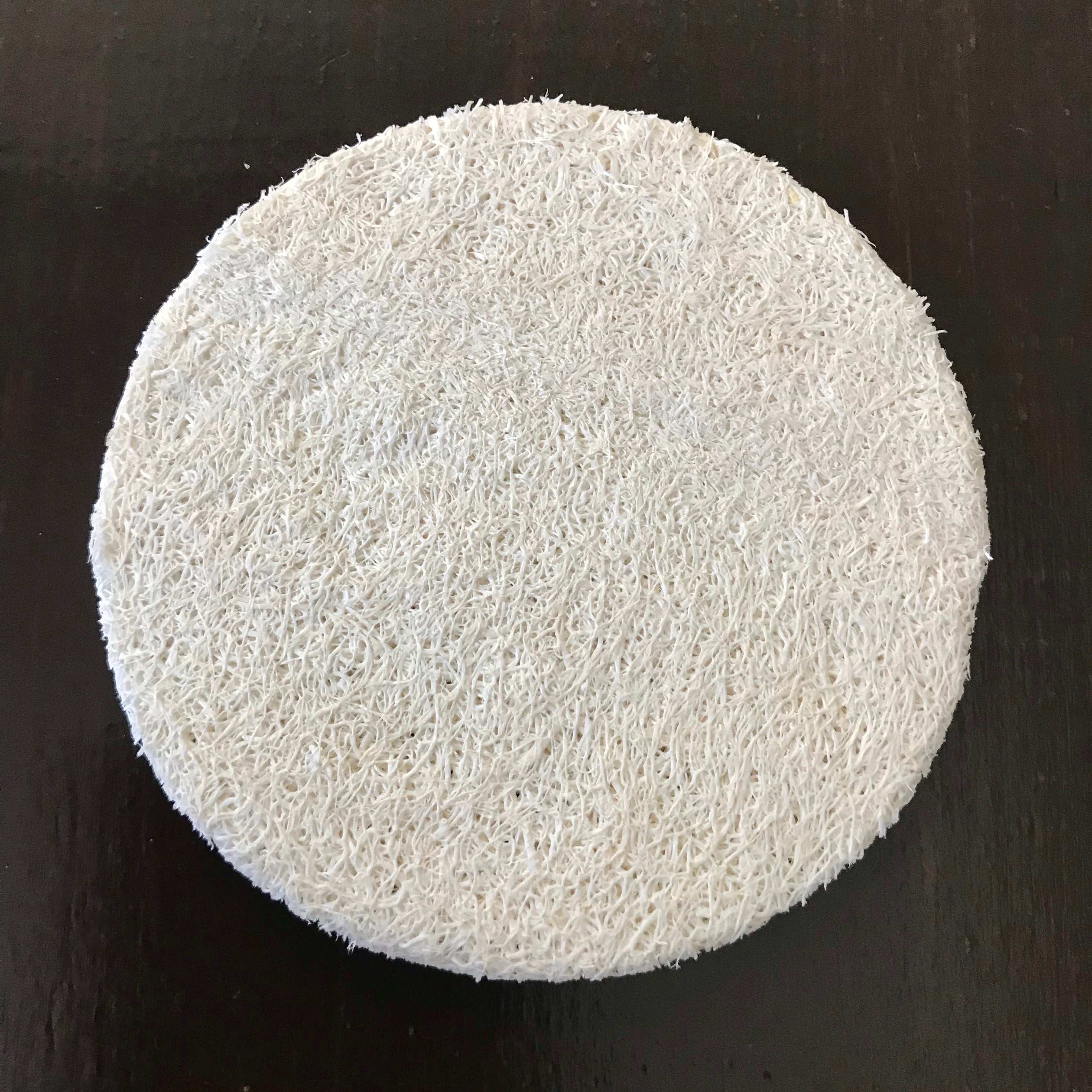 Close-up of the textured, natural loofah fibers highlighting its porous surface and hand-stitched edges for gentle