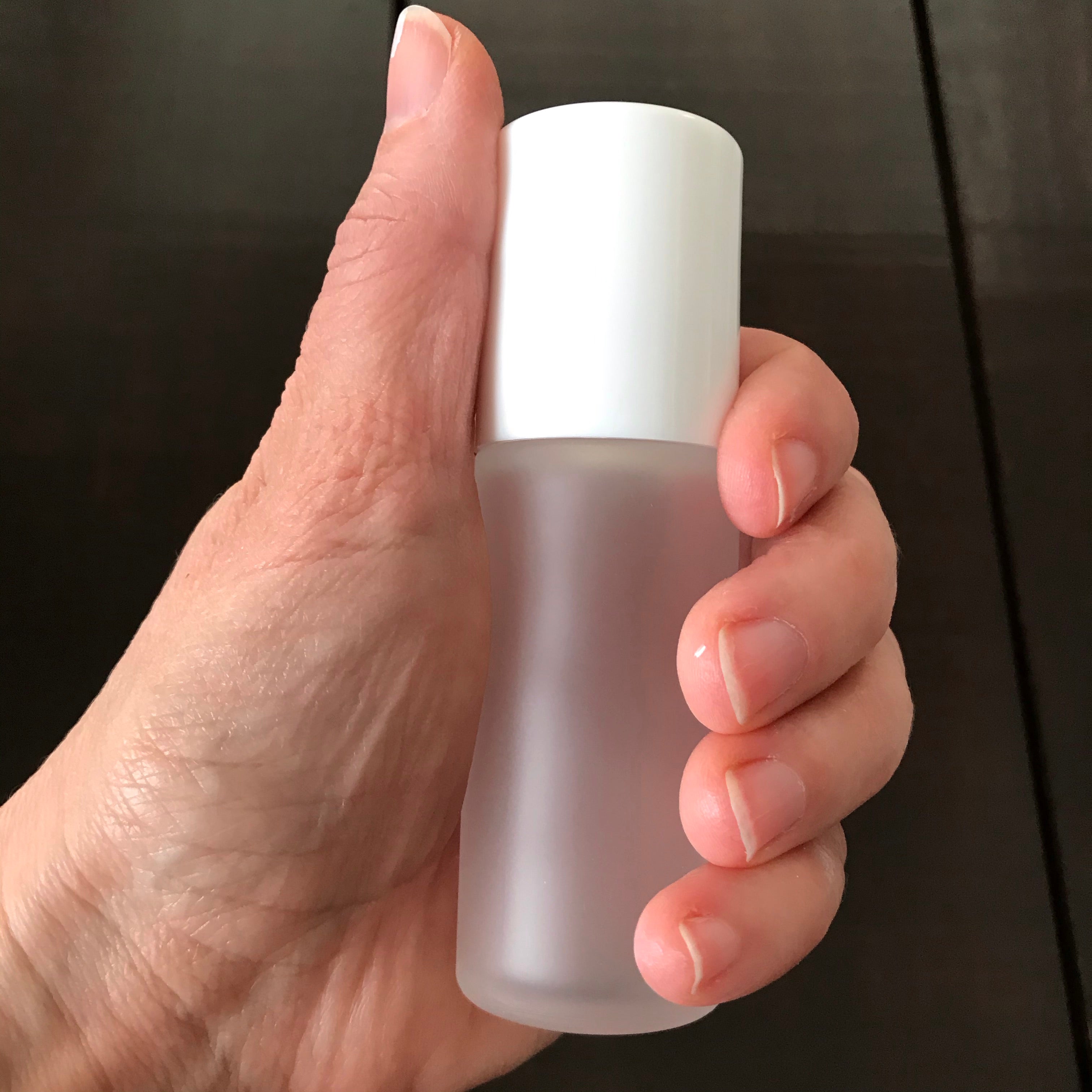 Close-up of clear plastic roll-on applicator with smooth, rounded tip, showing transparent lid and white deodorant gel inside
