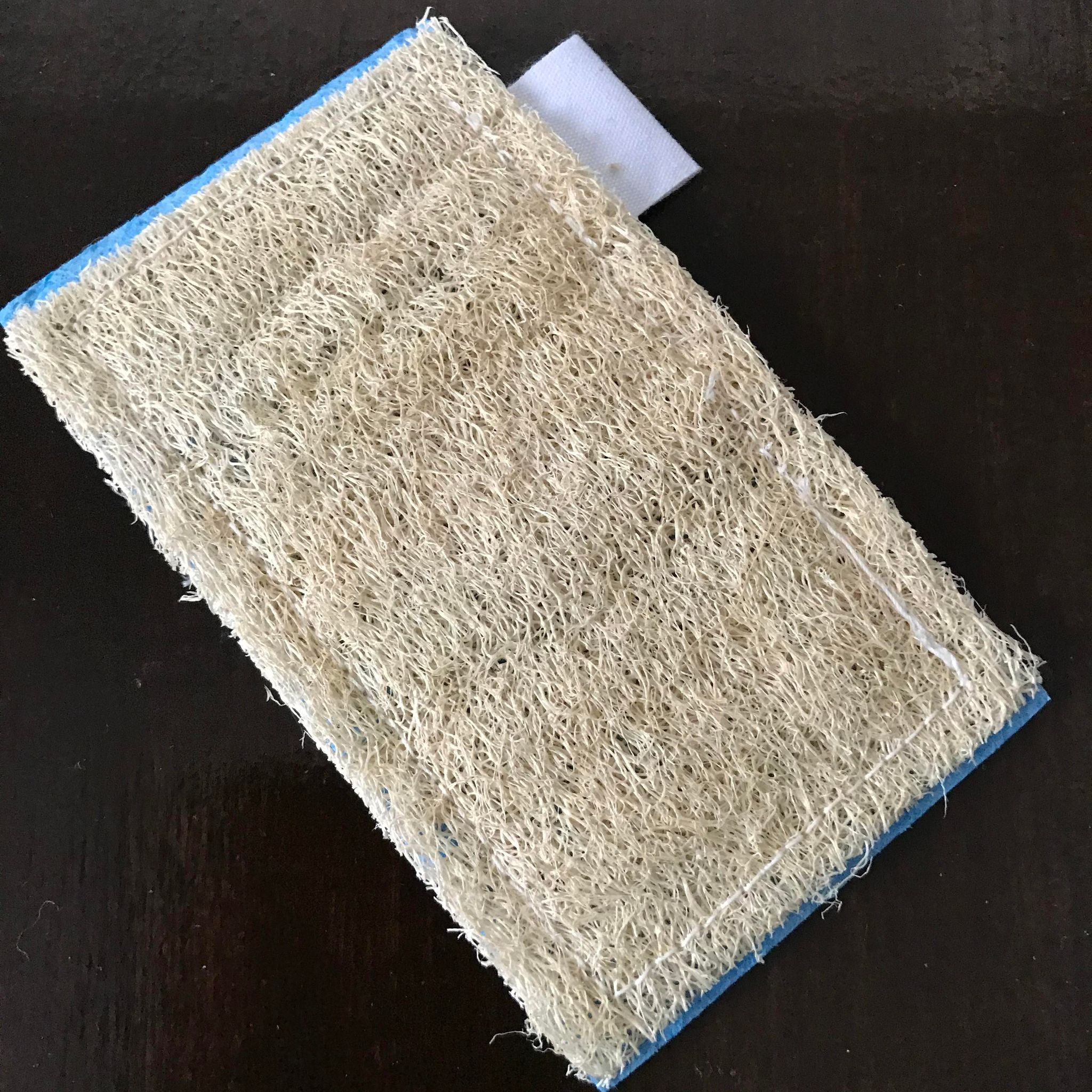 Close-up of the Loofie Scrubber's textured coconut fiber bristles and flexible silicone handle in vibrant green color