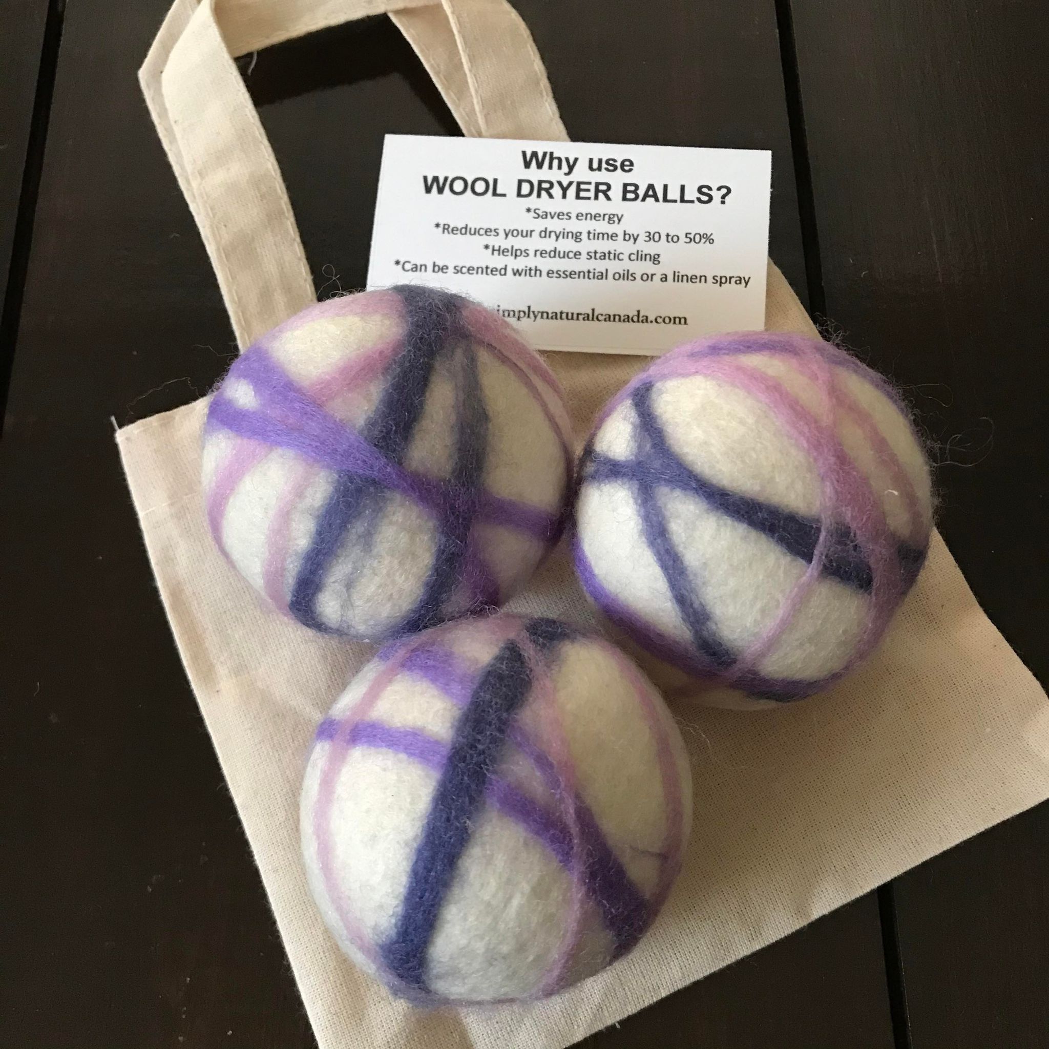 Close-up of three natural wool dryer balls in soft cream, highlighting their fuzzy, textured surface and compact size.
