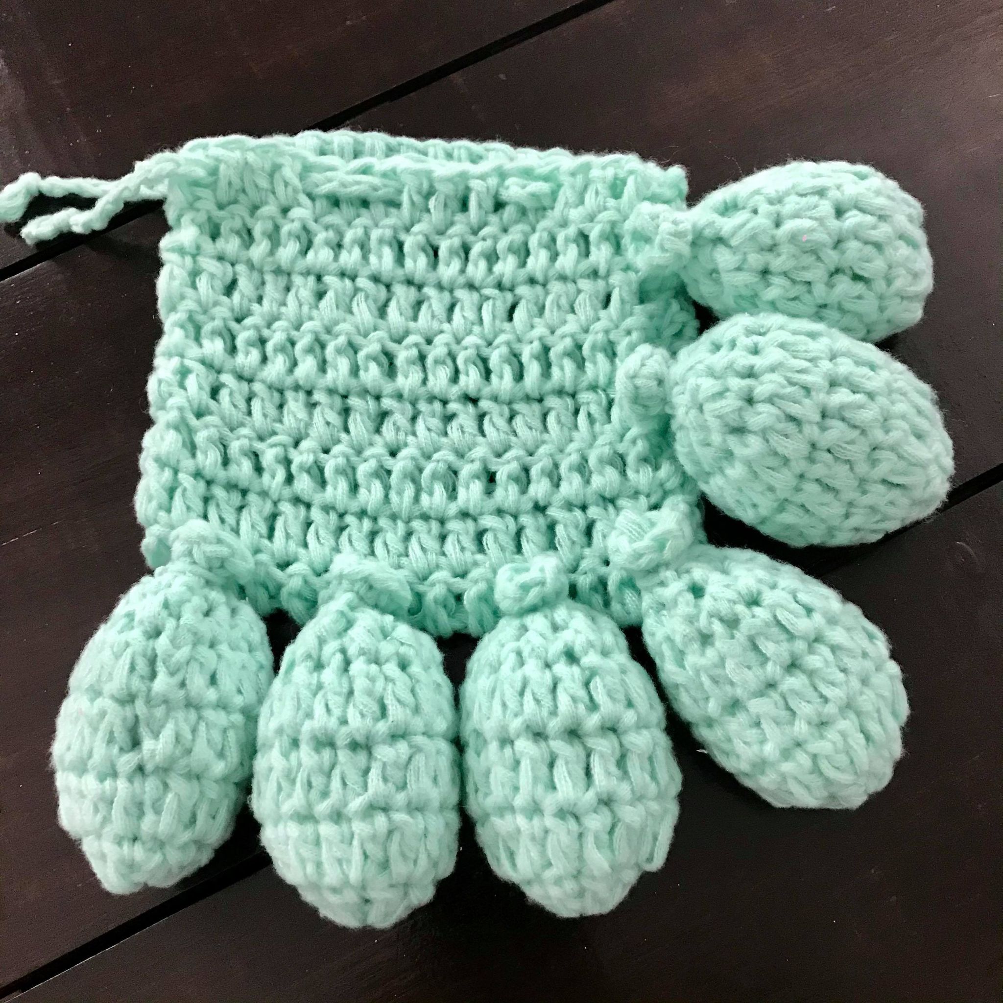 Close-up of handcrafted crochet water balloons showing colorful, tightly woven textured fabric with small, elastic openings